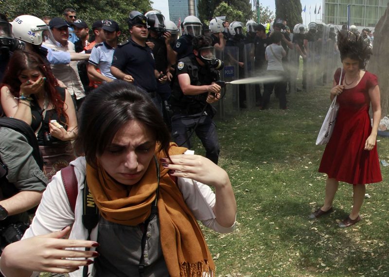 Turkish riot policeman uses tear gas during a protest in central Istanbul