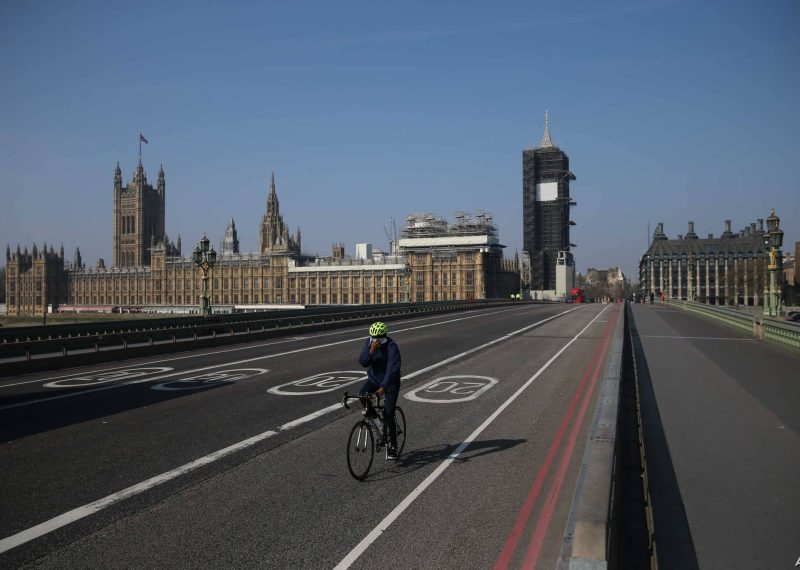 A cyclist crosses a near-empty Westminster Bridge with the Houses of Parliament in the background in central London on April 9, 2020. - British Prime Minister Boris Johnson on Thursday began a fourth day in intensive care "improving" in his battle with coronavirus, as his government prepared to extend a nationwide lockdown introduced last month. (Photo by ISABEL INFANTES / AFP)
