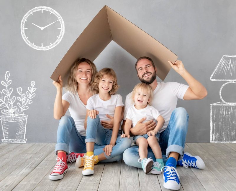 Happy family with two kids playing into new home. Father, mother and children having fun together. Moving house day and real estate concept