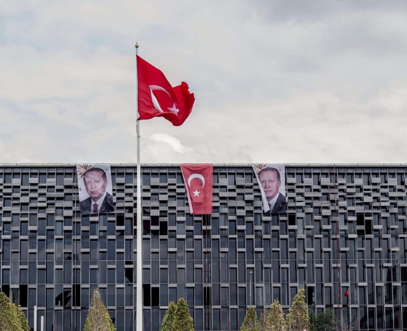 Banners with photographs of Recep Tayyip Erdogan, Turkey's president, hang from the roof of a commercial building either side of a Turkish national flag in Istanbul, Turkey, on Monday, July 18, 2016. Tourism is an essential source of foreign currency to finance Turkey's current-account deficit and employs 8 percent of the nation's workforce. Photographer: Ismail Ferdous/Bloomberg via Getty Images